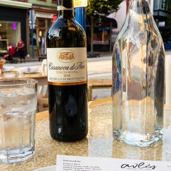 Outdoor dining table with a bottle of Casanova di Neri wine, water, and a glass of red wine.