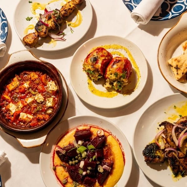Overhead view of a table laden with various Greek dishes, including grilled meats, pita, and vegetable plates.