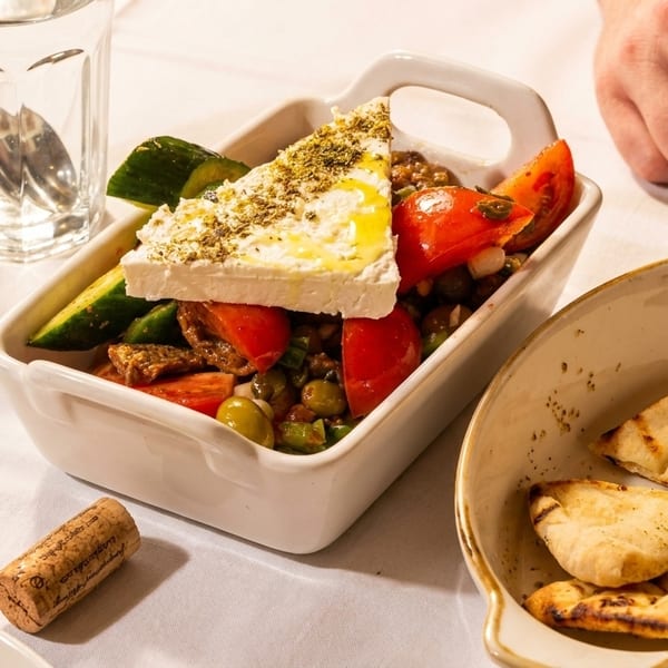 A Greek salad with feta, tomatoes, cucumbers, and olives, served with pita bread.